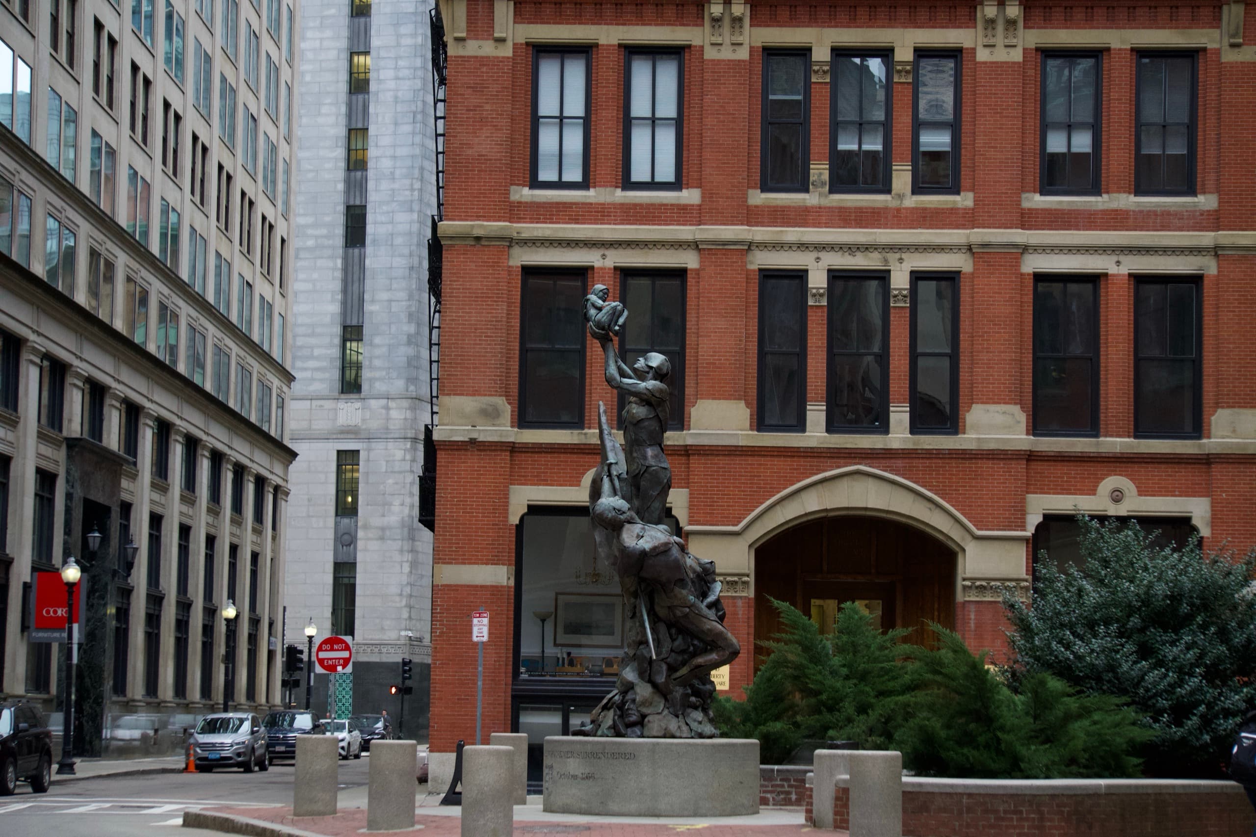 A bronze memorial against red brick city buildings