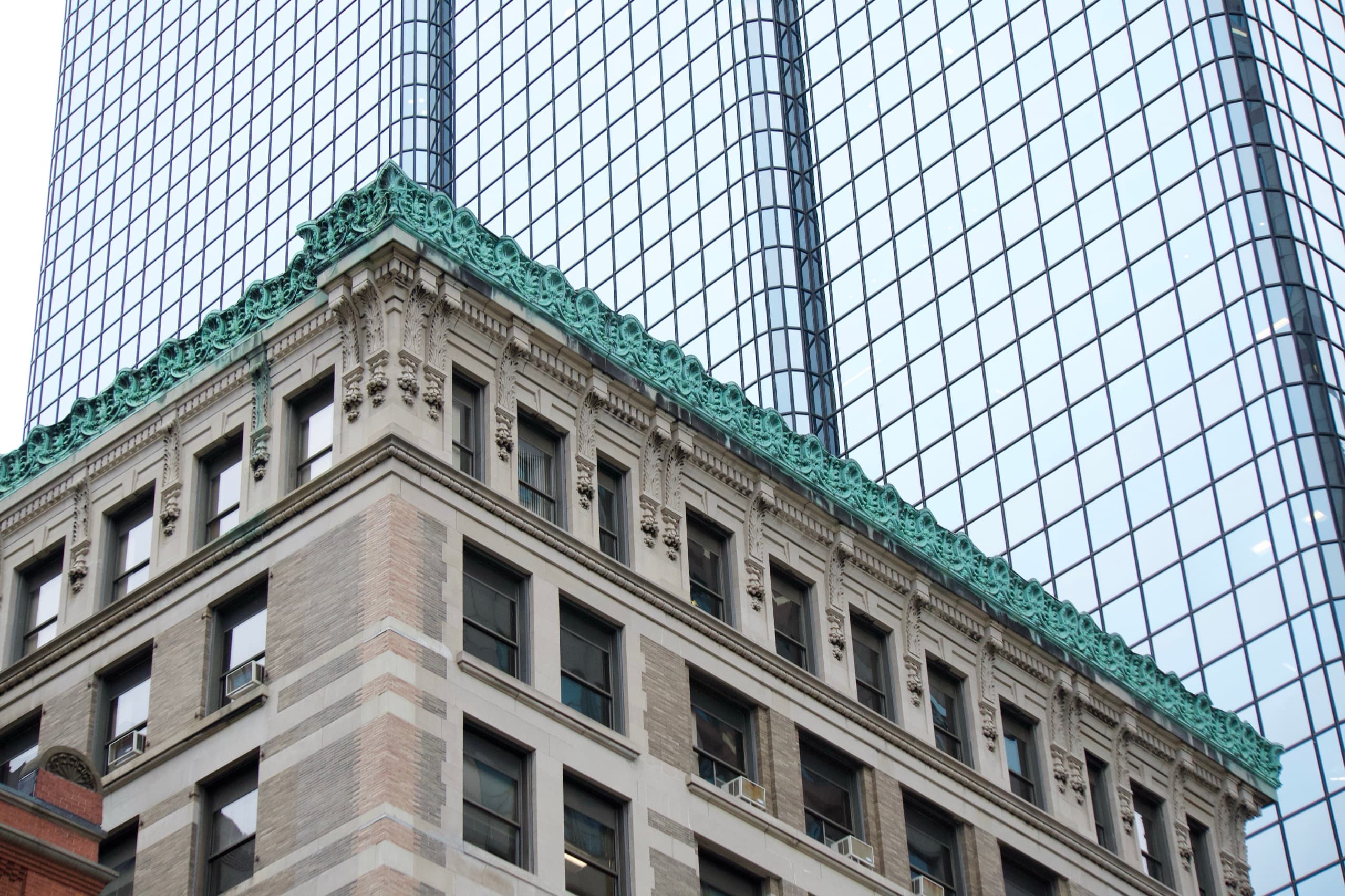 A stone building beneath a modern glass tower