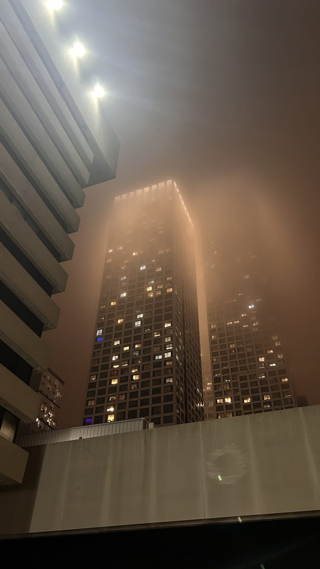 Illuminated buildings disappearing into night fog