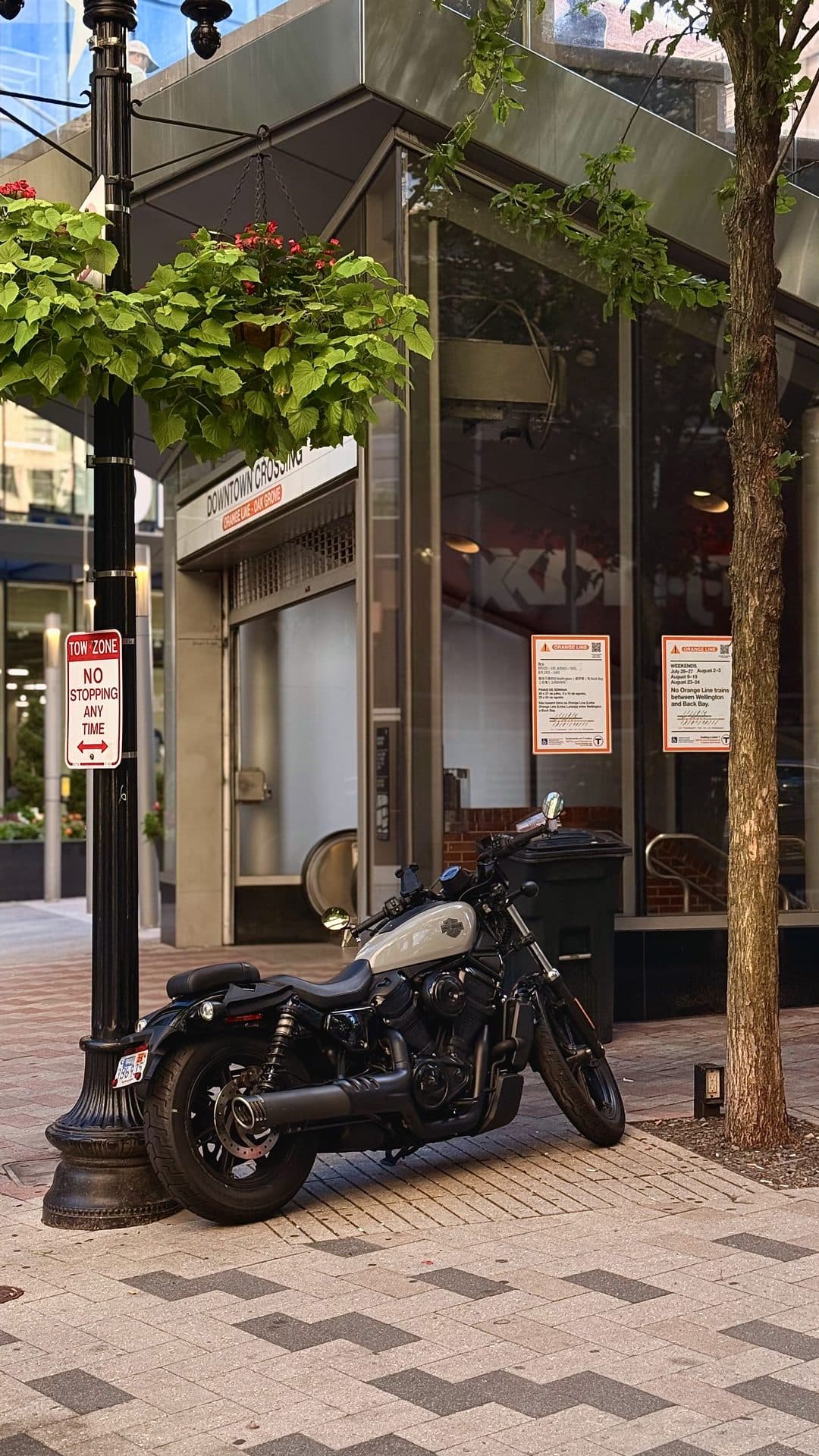 A quiet sidewalk with a parked motorcycle and trees