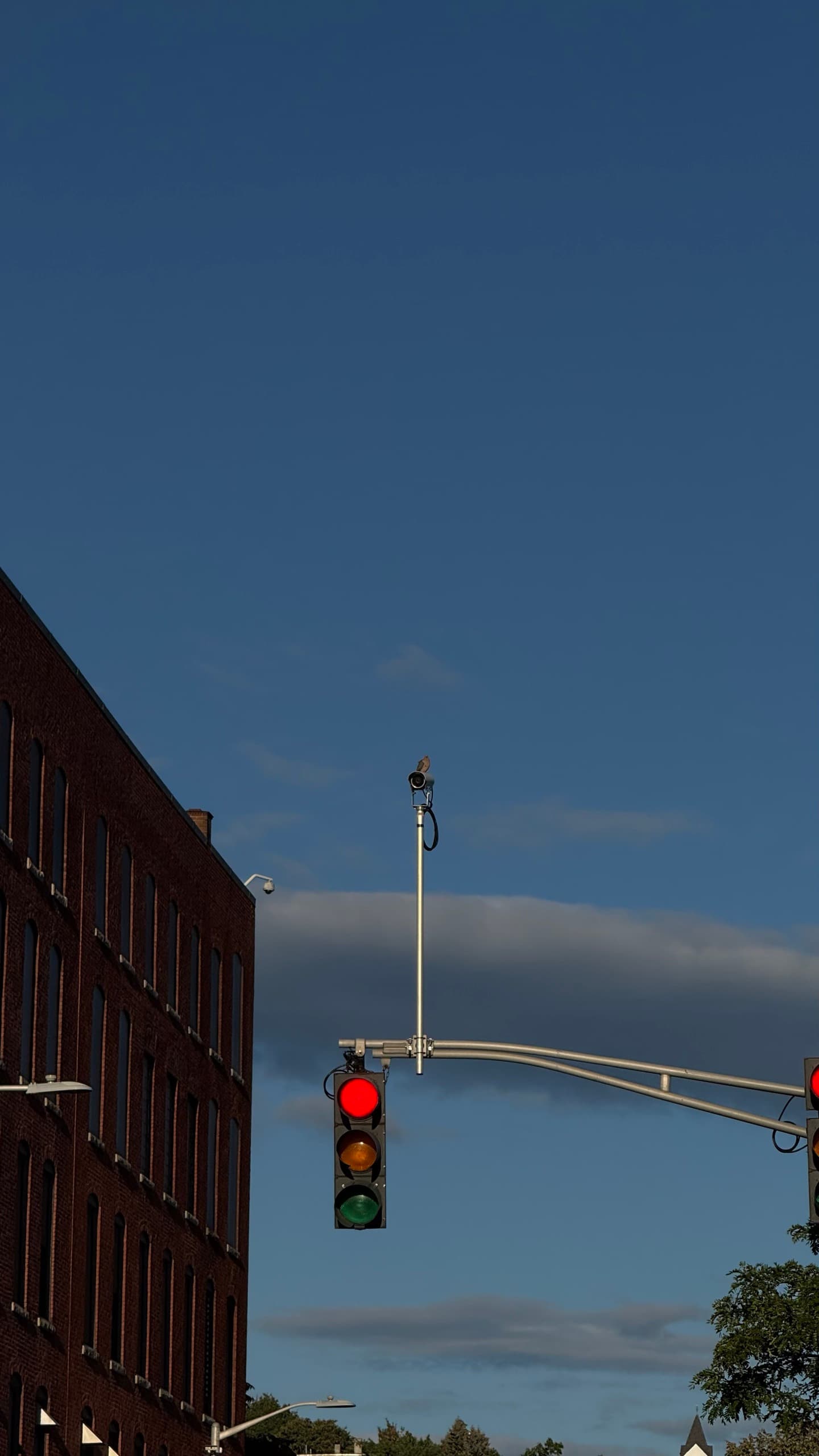 A traffic signal beside a brick building at dusk