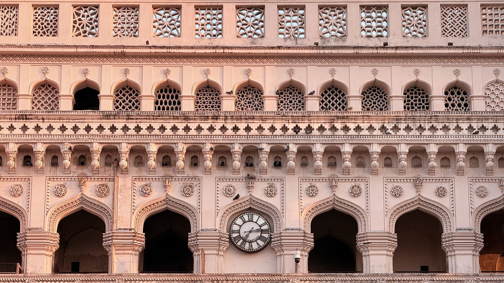 An ornate facade with rows of arches and a central clock