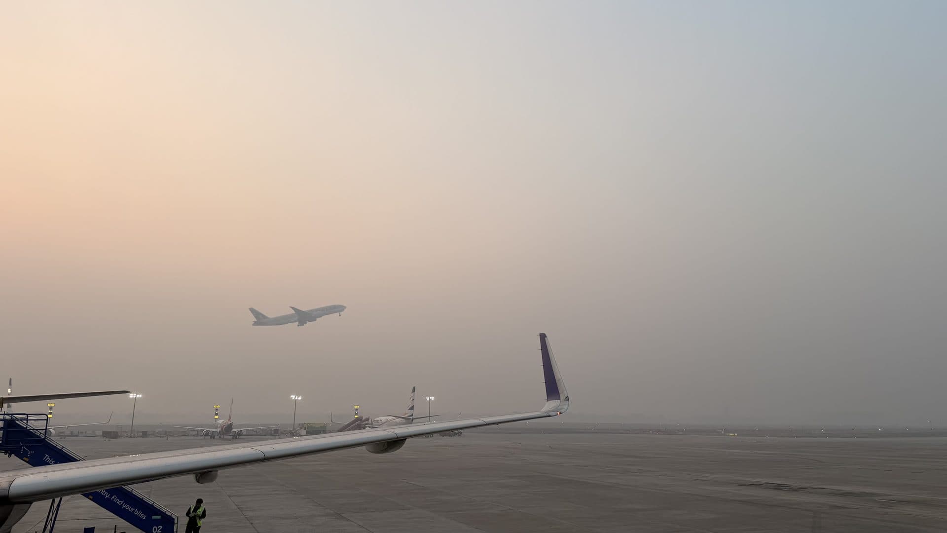 An airplane wing on a hazy runway