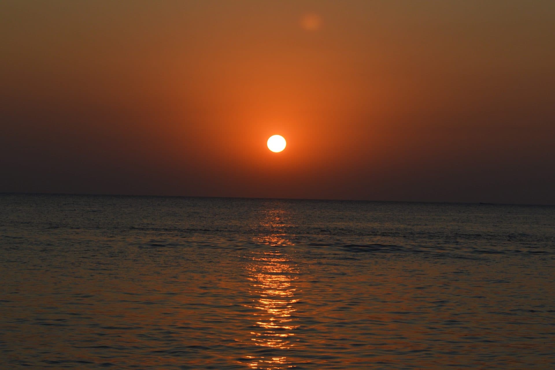 An orange sun setting over the sea